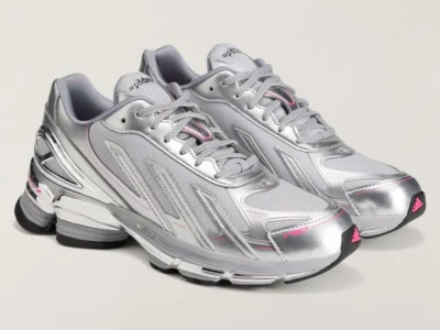 Three-quarter angled view of the pair displaying the streamlined F50-inspired silhouette. Metallic silver overlays contrast with breathable mesh panels, while pink adidas branding on the toe bumper adds a vibrant accent