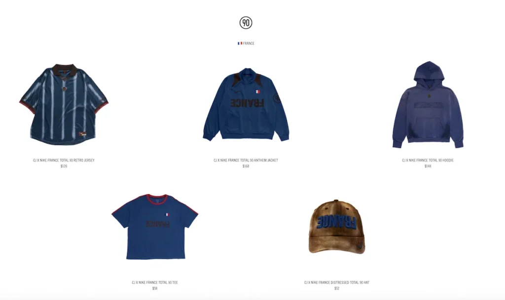 France-inspired Cactus Jack x Nike Total 90 collection featuring a navy retro football jersey with tonal striping, blue anthem jacket with inverted “FRANCE” lettering, soft blue hoodie, matching blue T-shirt, and a weathered brown cap embroidered with “FRANCE” in blue