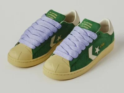 Green suede Converse Pro Leather by le FLEUR* with oversized lavender rope laces, cream Star Chevron logo, vintage yellowed sole, and off-white heel tab shown from a front three-quarter angle