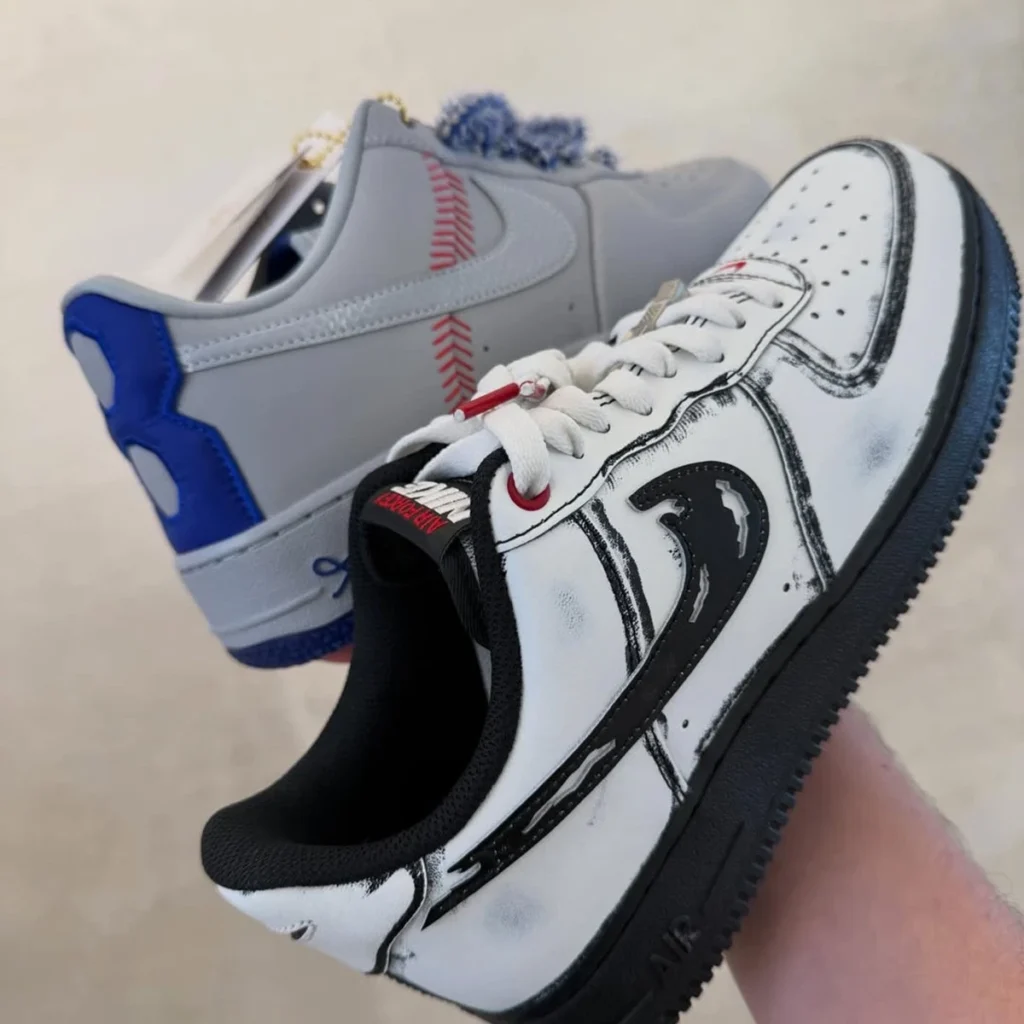 Pair of custom Nike Air Force 1 shoe shown together, with one baseball-inspired gray colorway featuring stitched seam graphics and blue accents, alongside a distressed white-and-black sketch-style Air Force 1 with red eyelets and lace dubrae detail