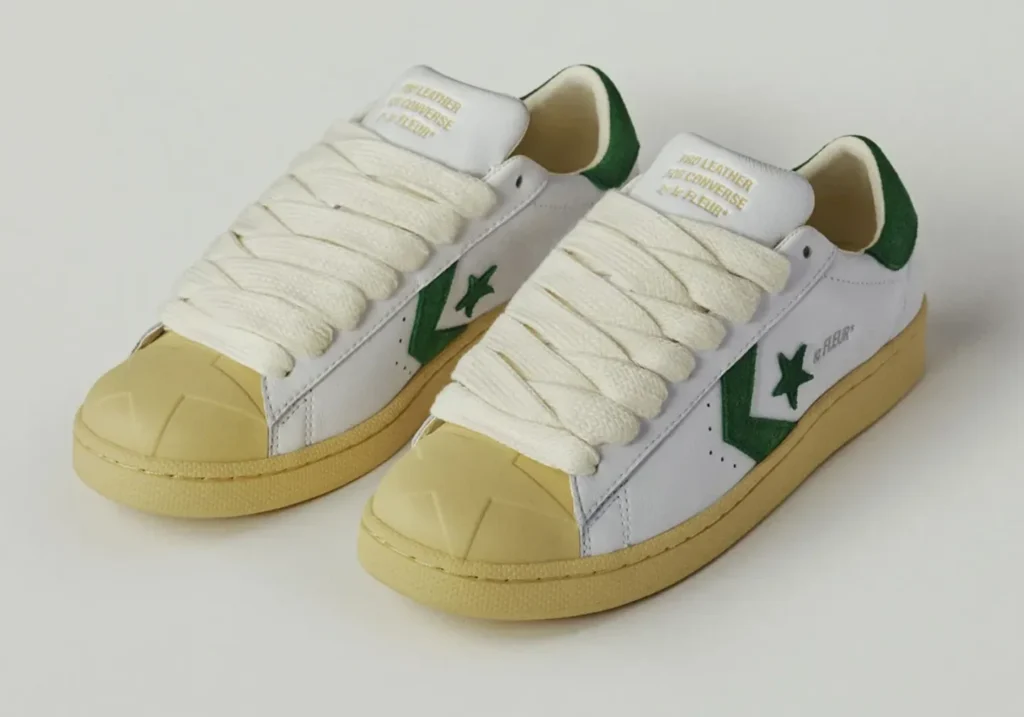 White leather Converse Pro Leather by le FLEUR* featuring oversized cream rope laces, green suede Star Chevron logo, green heel tab, and aged cream sole viewed from the front