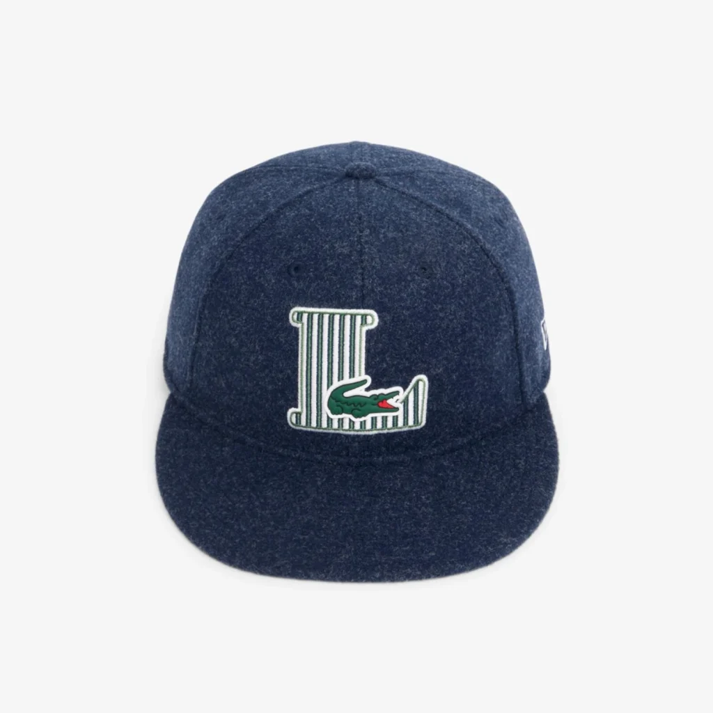 Navy wool-look flat-brim cap with a large embroidered striped "L" monogram and Lacoste crocodile logo centered on the front panel