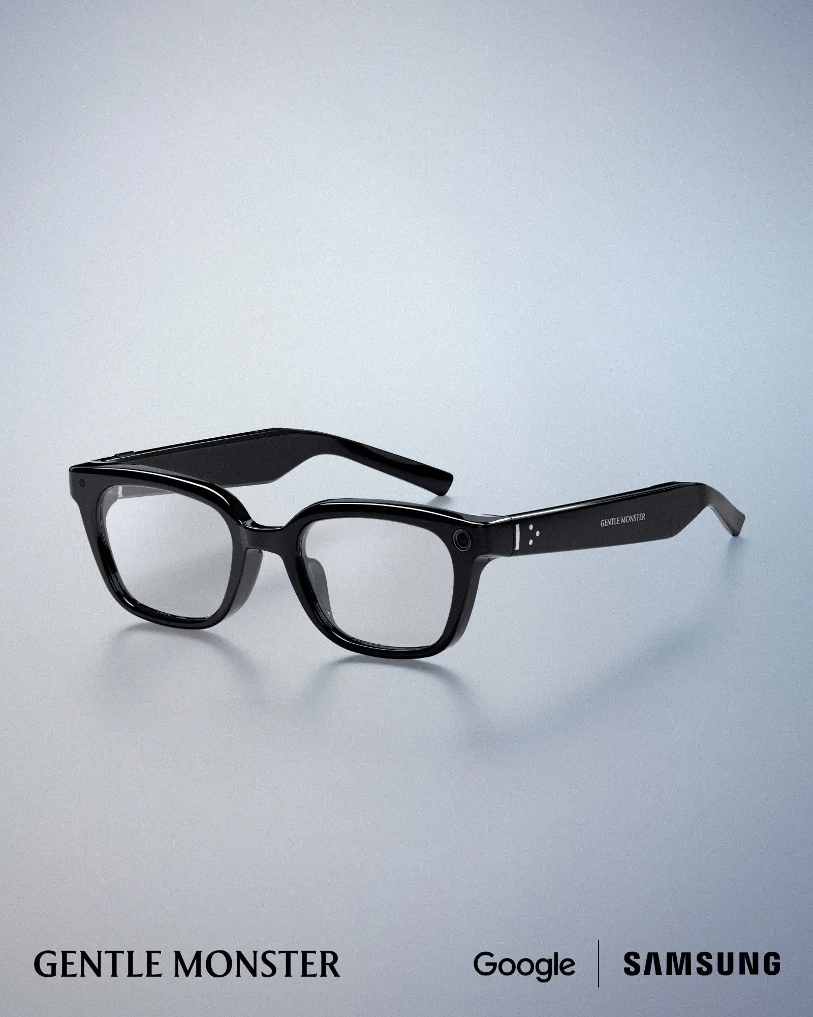 Black Gentle Monster AI smart glasses with clear prescription lenses, rectangular glossy acetate frames, integrated front-facing camera and touch controls, developed with Samsung and Google, shown on a clean white studio background.