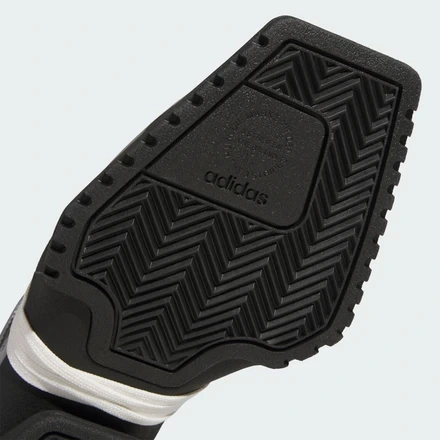 Close-up of the adidas Forum SQ outsole featuring a black rubber herringbone traction pattern, embossed adidas branding, and the extended square forefoot platform with industrial-inspired detailing.