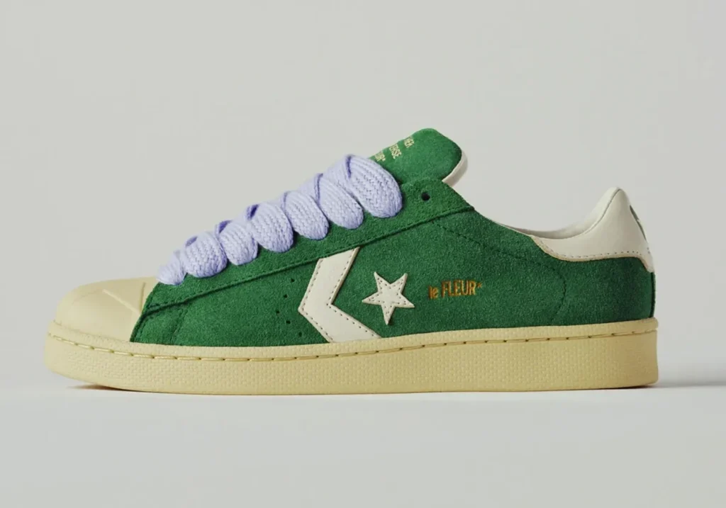 Lateral side profile of the green suede Converse Pro Leather by le FLEUR* with cream Star Chevron logo, embroidered le FLEUR* branding, oversized lavender laces, and vintage yellow sole