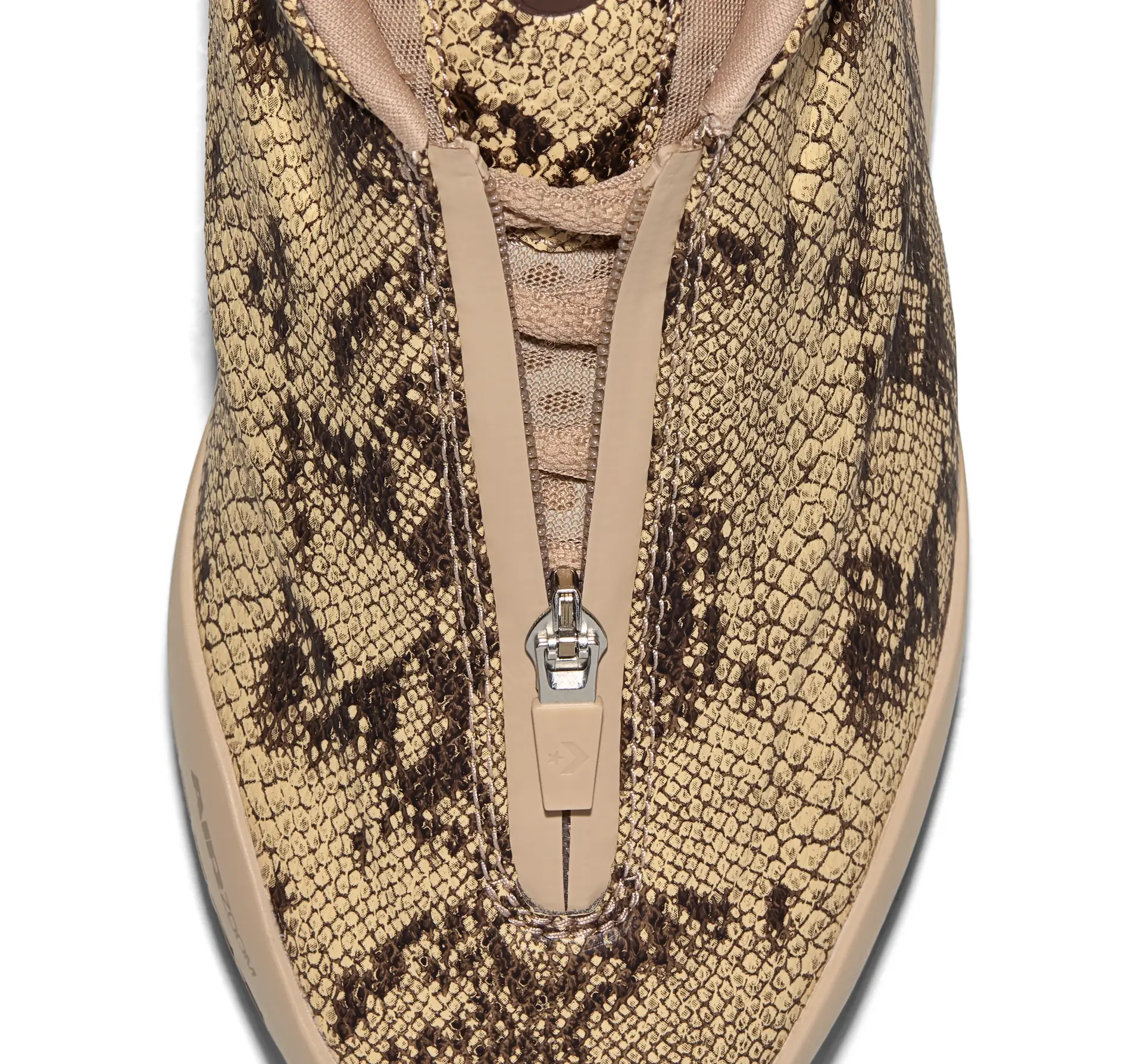 Close-up top view of the Converse SHAI 001 PREMIUM: Slither, showcasing its embossed snakeskin textured synthetic leather upper in tan and black. The centered zipper shroud conceals the lacing system, while the neutral beige trim and sculpted silhouette highlight the shoe's premium construction against a clean white background.