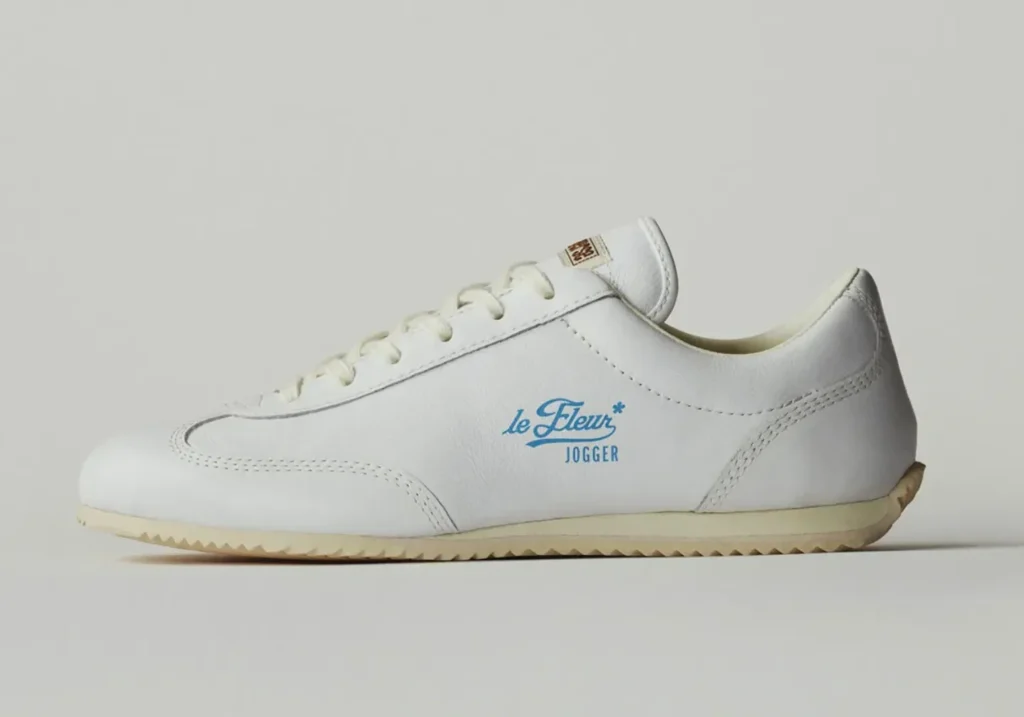 Lateral side profile of the white Converse le FLEUR* Jogger with minimalist white leather upper, blue le FLEUR* Jogger branding, cream outsole, and retro running shape