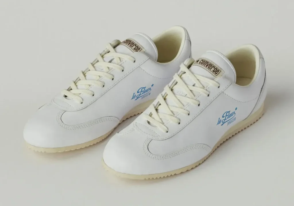 Front three-quarter view of the white Converse le FLEUR* Jogger featuring smooth white leather construction, cream laces, blue side branding, and low-profile vintage-inspired outsole