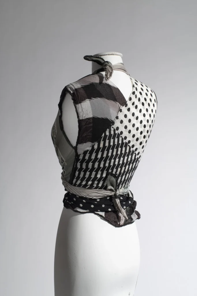 Patchwork wrap top crafted from mixed monochrome printed fabrics including polka dots, stripes, and geometric motifs, tied around a dress form
