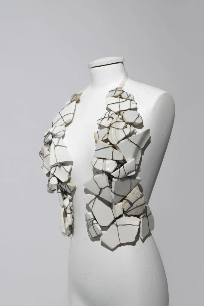 Statement necklace assembled from broken white ceramic fragments bound together with exposed wire, creating a sculptural wearable artwork