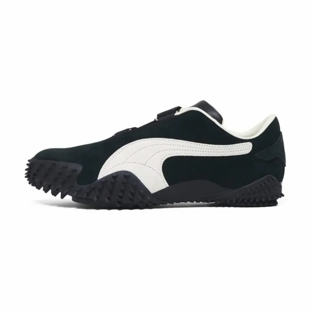 Side view of a black suede Puma x JJJJound shoe with white Formstrip, black velcro strap, and aggressive black nubbed rubber outsole