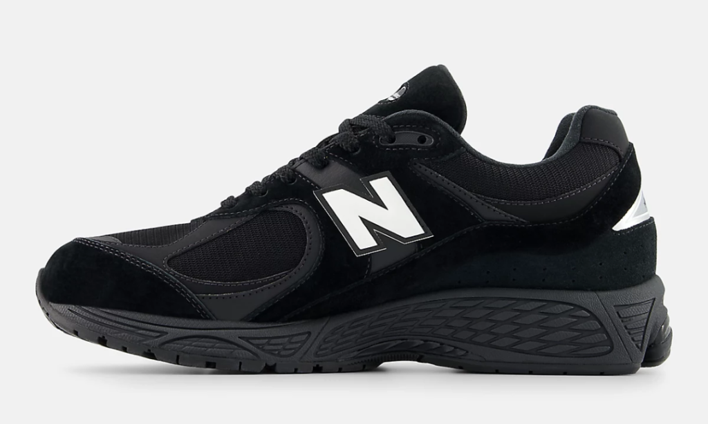 Medial side view of the New Balance 2002R GORE-TEX in an all-black colorway, highlighting layered suede and mesh construction, sculpted cushioning midsole, rugged outsole, and reflective heel accent for weather-ready show