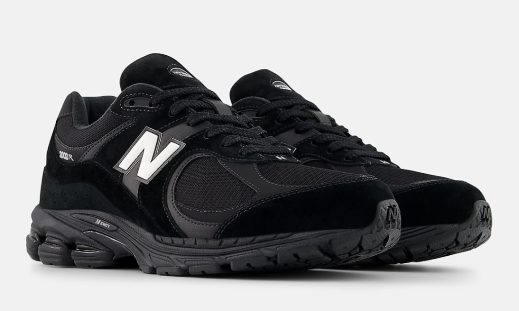 Three-quarter angled view of the New Balance 2002R GORE-TEX sneakers displaying premium black suede mudguards, breathable mesh panels, oversized white "N" logos, and chunky ABZORB sole units with an all-black finish