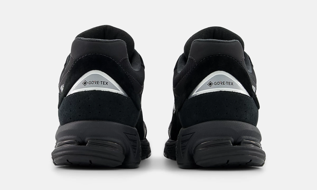 Rear view of the New Balance 2002R GORE-TEX revealing reflective silver heel tabs with GORE-TEX branding, perforated suede heel overlays, padded collars, and thick black cushioning pods beneath the heel