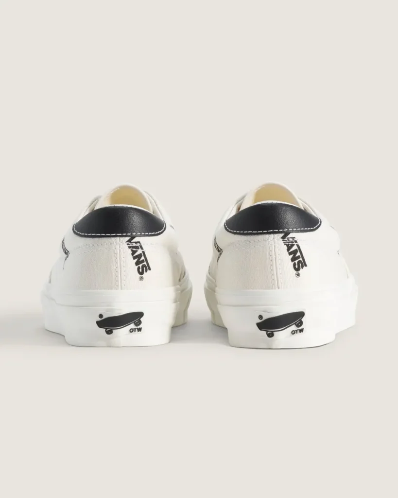 Rear view of the white Vans OTW sneakers displaying black leather heel patches, vertical Vans logo graphics, and OTW skateboard heel brand on the white rubber heel tab