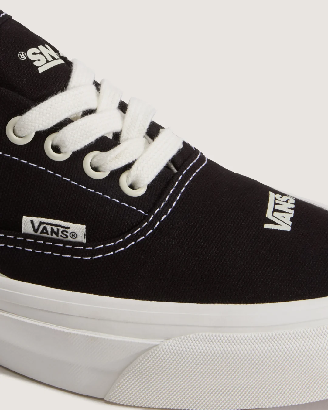 Close-up of the black Vans OTW low-top sneaker highlighting the textured canvas upper, oversized white Vans logo on the toe box, woven Vans side tab, white contrast stitching, thick cotton laces, and textured white rubber foxing.