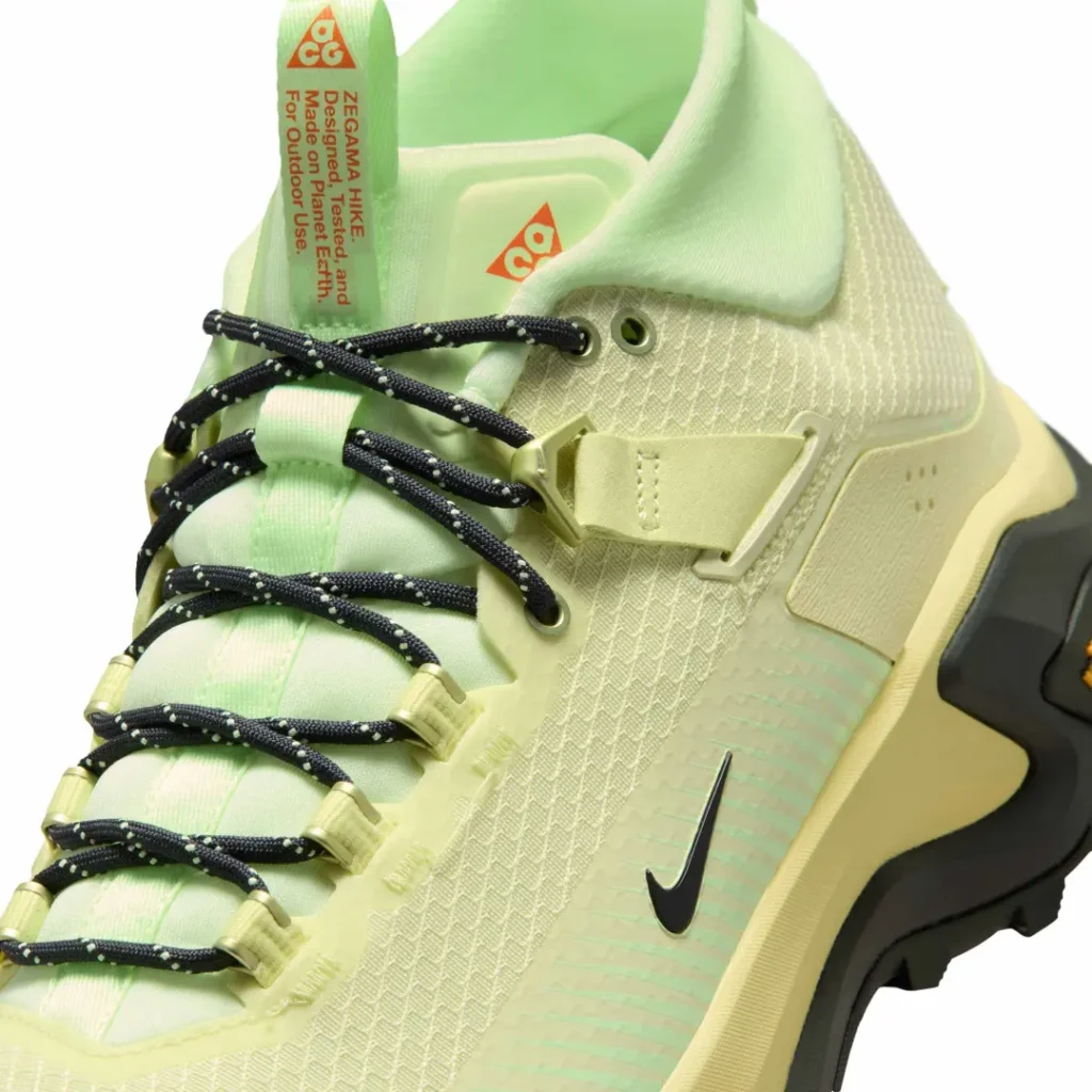 Close-up of the pale volt Nike ACG Zegama Hike highlighting the woven upper, reinforced eyelets, technical lacing hardware, and black Nike Swoosh