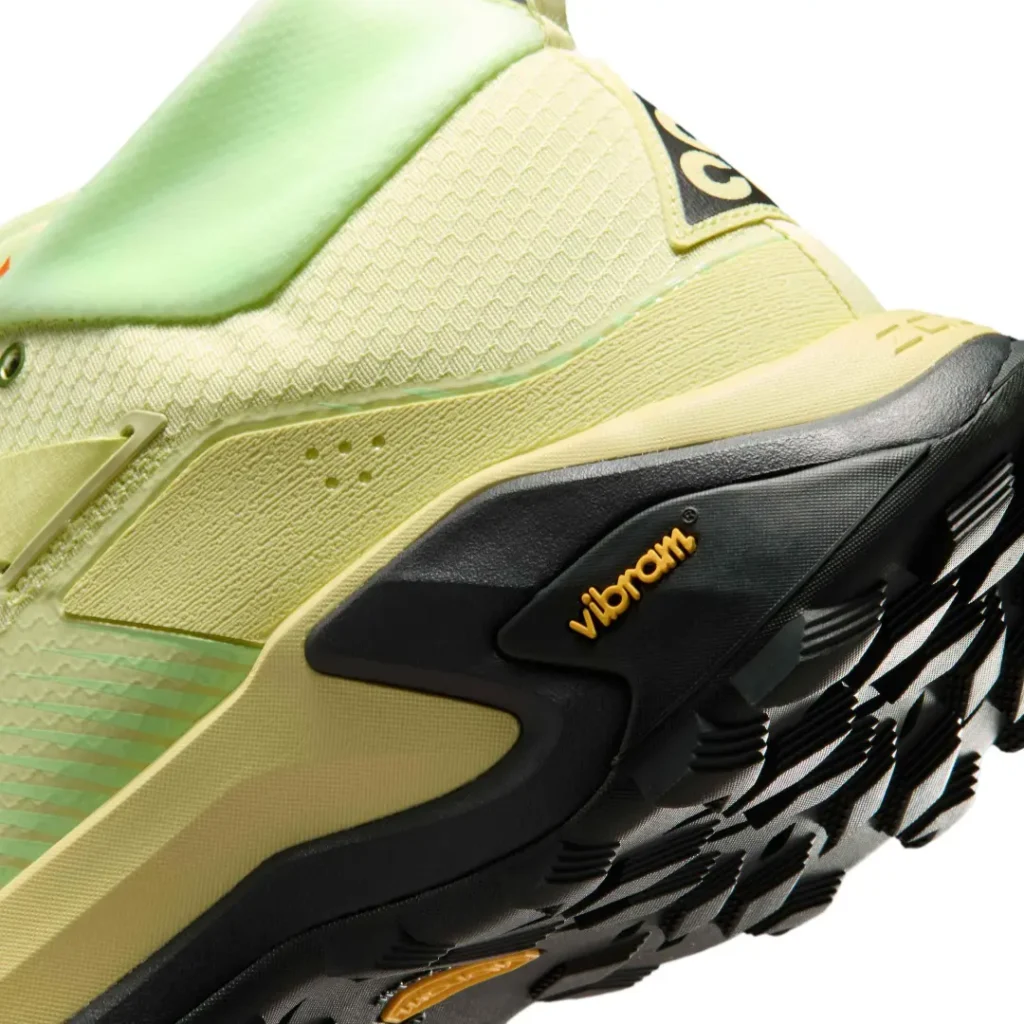 Macro detail of the pale volt Nike ACG Zegama Hike heel showcasing the Vibram-branded outsole, sculpted foam midsole, and rugged trail traction pattern