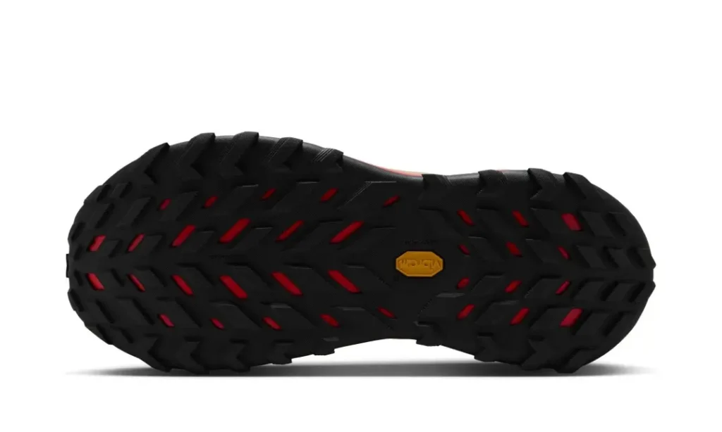 Bottom view of the Nike ACG Zegama Hike highlighting the aggressive black Vibram rubber outsole with deep multidirectional trail lugs and red cutout accent