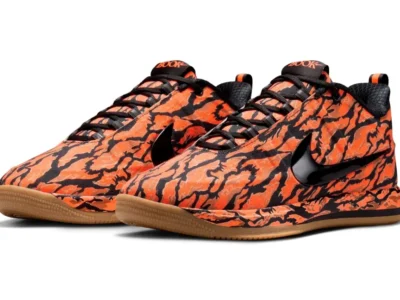 Pair of Nike Book 2 basketball shoes in an orange-and-black camouflage colorway with glossy black Swooshes and gum rubber outsole