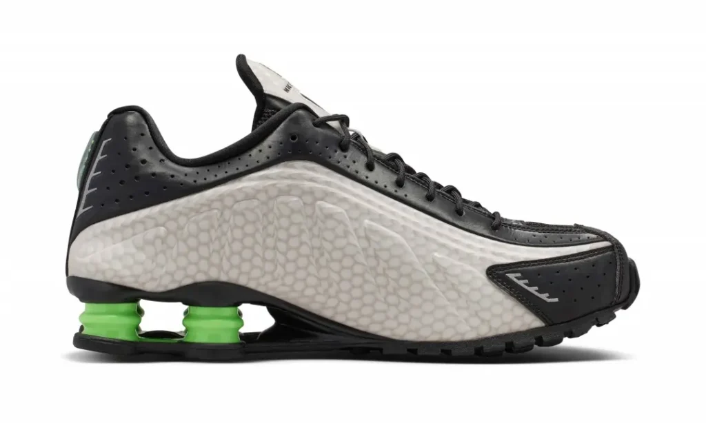 Medial side profile of the Nike Shox TL displaying the sculpted sidewall, black overlays, and green Shox column