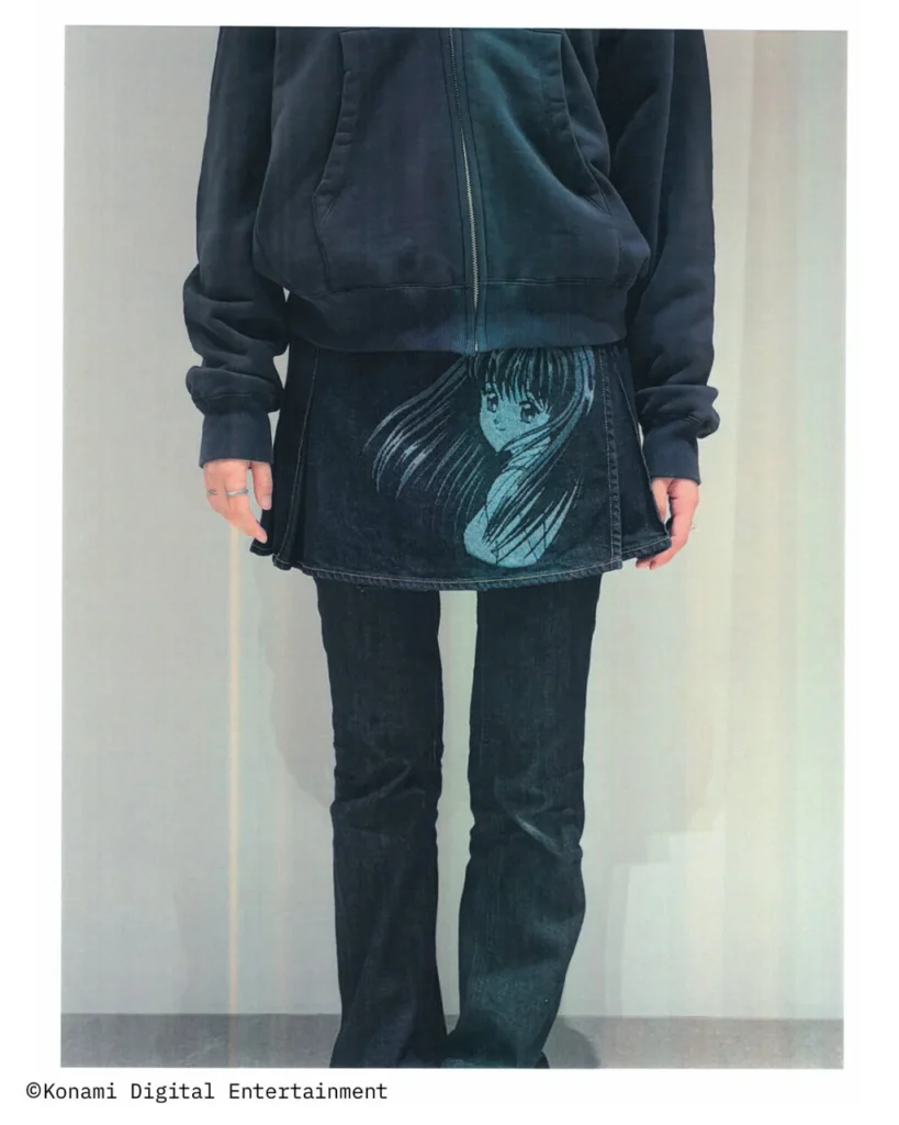 Black denim mini skirt featuring a monochrome manga character graphic on the front, styled with a black zip hoodie and dark flared jean