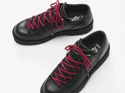 Pair of black leather Danner low hiking shoes with burgundy laces displayed diagonally on a white studio background