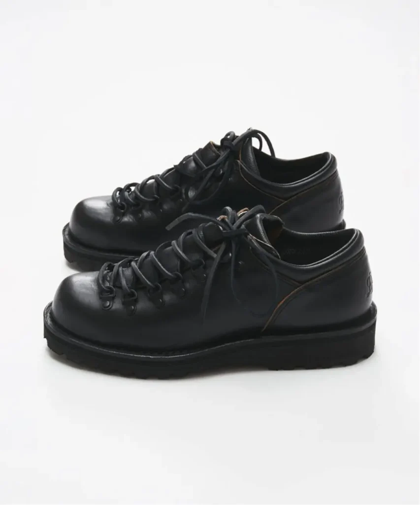Side profile of a pair of black leather Danner hiking shoes with black leather laces and durable lugged sole