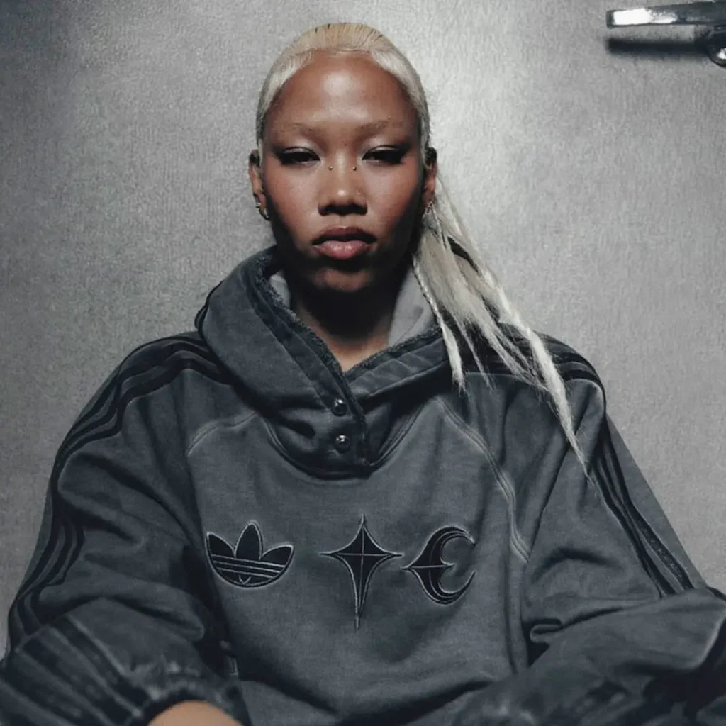 Campaign portrait of a model wearing a charcoal adidas Originals by Taqwa Bint Ali hoodie featuring co-branded chest graphic