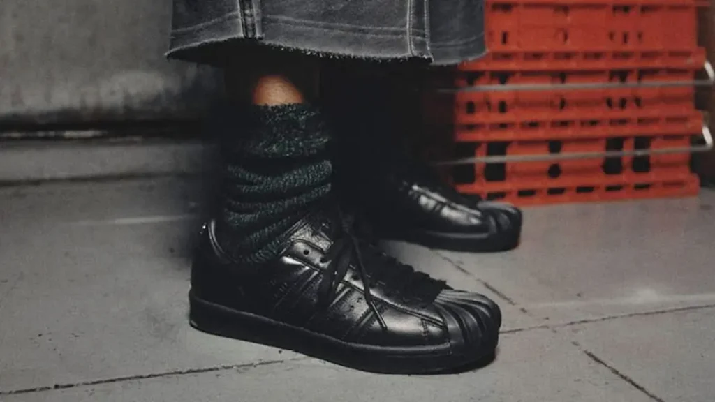 Close-up on the adidas Originals by Taqwa Bint Ali Superstar worn with textured socks, highlighting the sculptural black shell toe and premium leather upper
