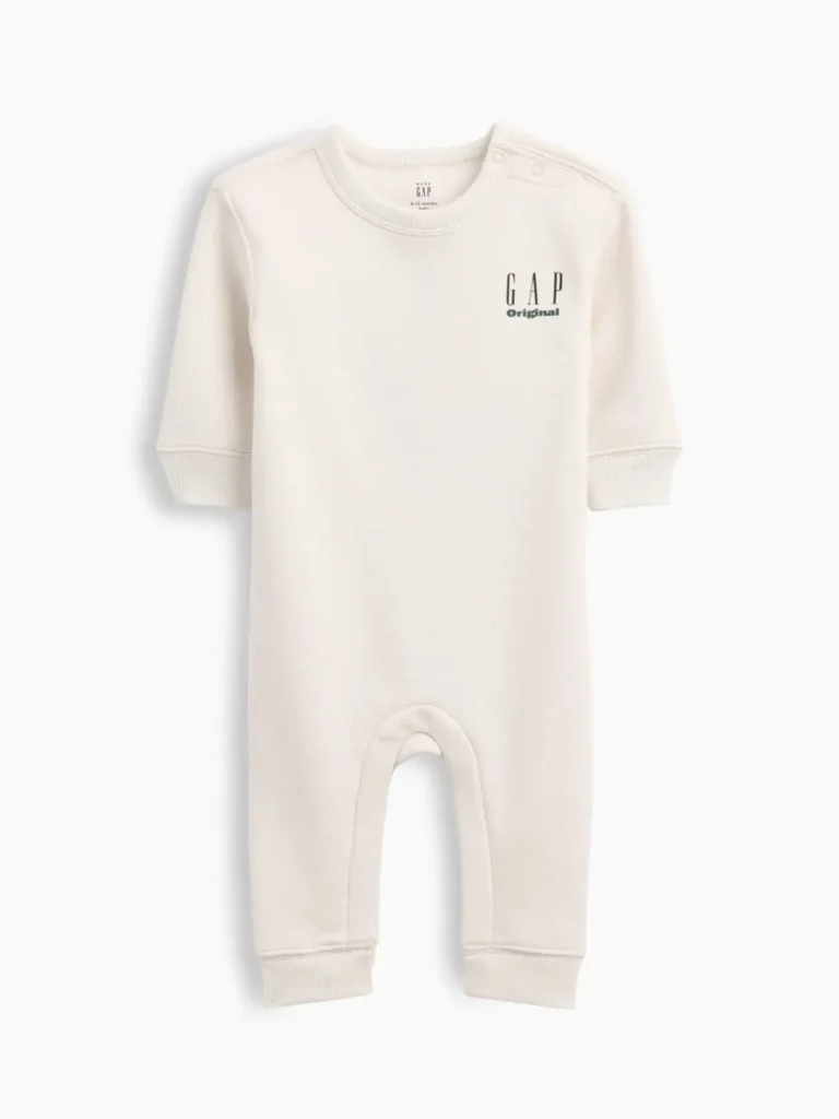 Cream baby long-sleeve romper with shoulder snap closures, ribbed cuffs, and a small black-and-green GAP Original logo on the left chest