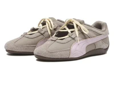 Pair of Puma low-profile shoe in taupe suede and textile, featuring pale pink Formstrips, cream rope laces, open cutout panels, and brown rubber soles against a white background