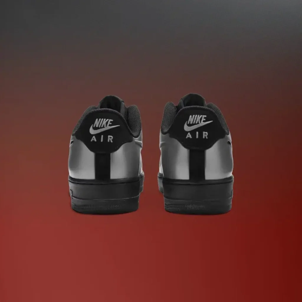 Rear view of a pair of metallic silver Nike Air Force 1 Low sneakers featuring black heel tabs with white Nike Air brand