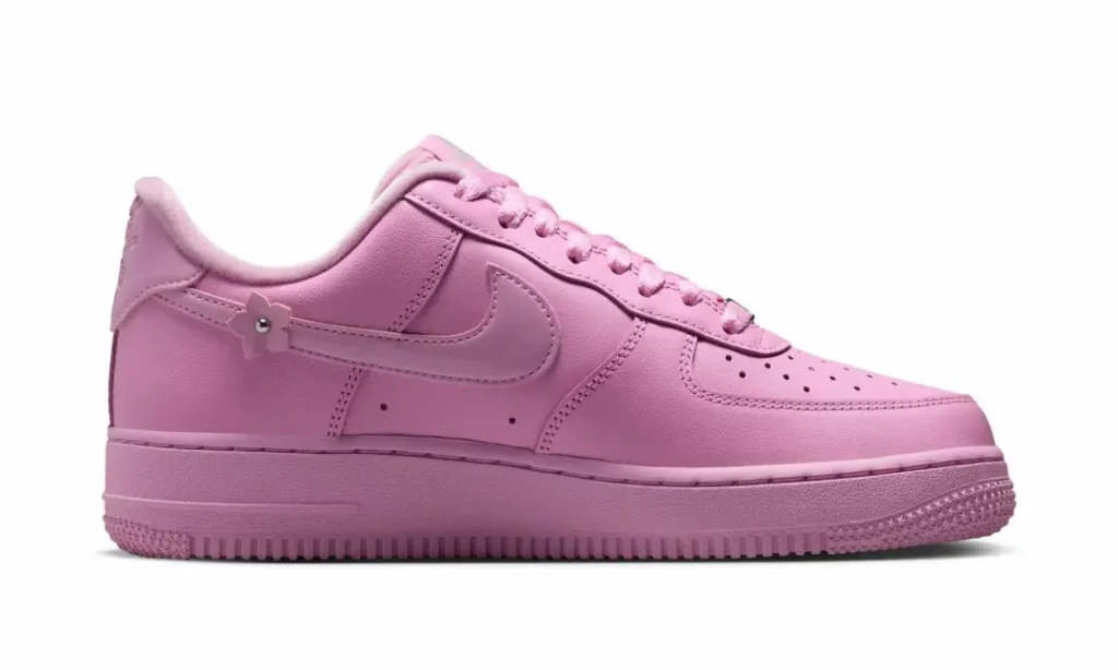 Medial side view of the pastel pink Nike Air Force 1 featuring a single flower charm near the heel