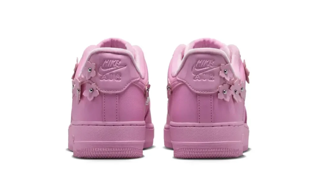 Rear view of the pastel pink Nike Air Force 1 highlighting embroidered Nike Air heel branding and flower lace charm