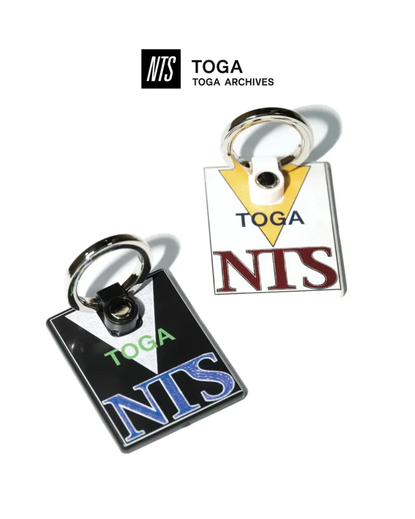 Two rectangular metal phone ring holders in black and white with co-branded TOGA and NTS graphic