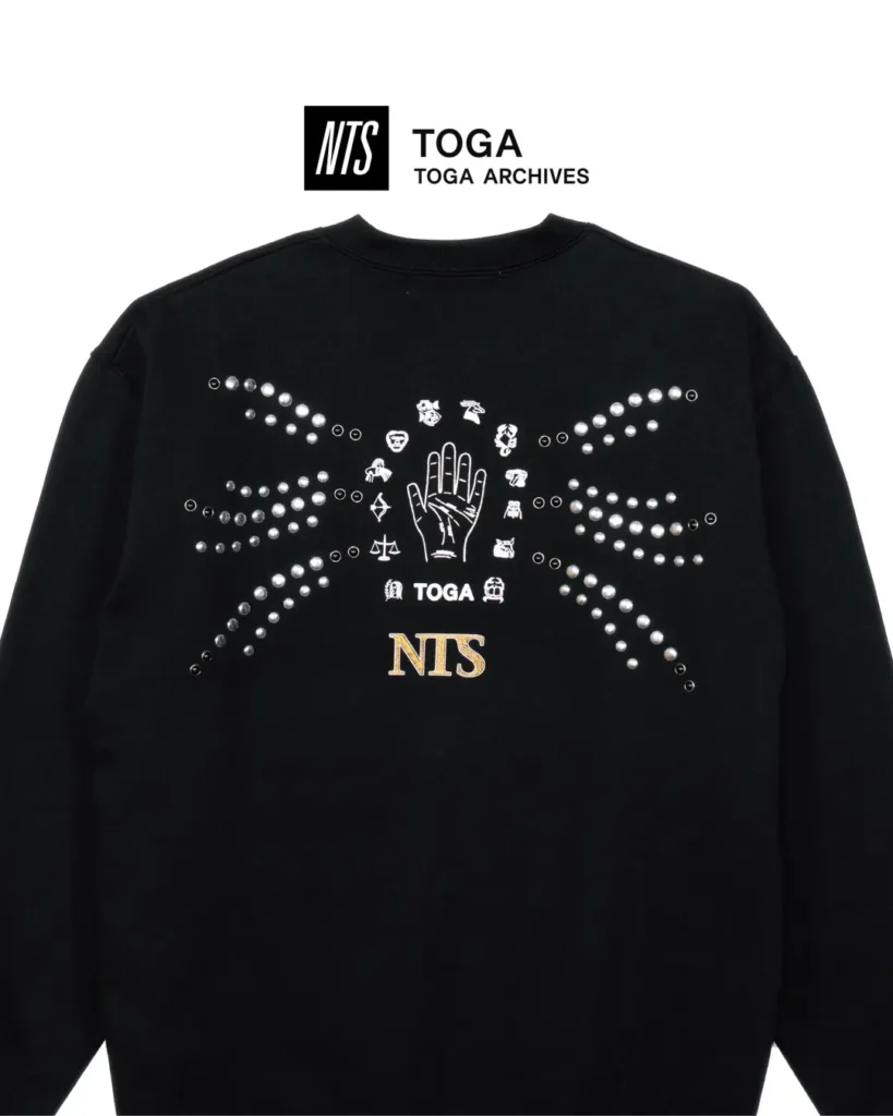 NTS x TOGA Archives graphic sweatshirt: Black crewneck sweatshirt with crystal embellishments, palmistry-inspired artwork, TOGA branding, and NTS logo on the back
