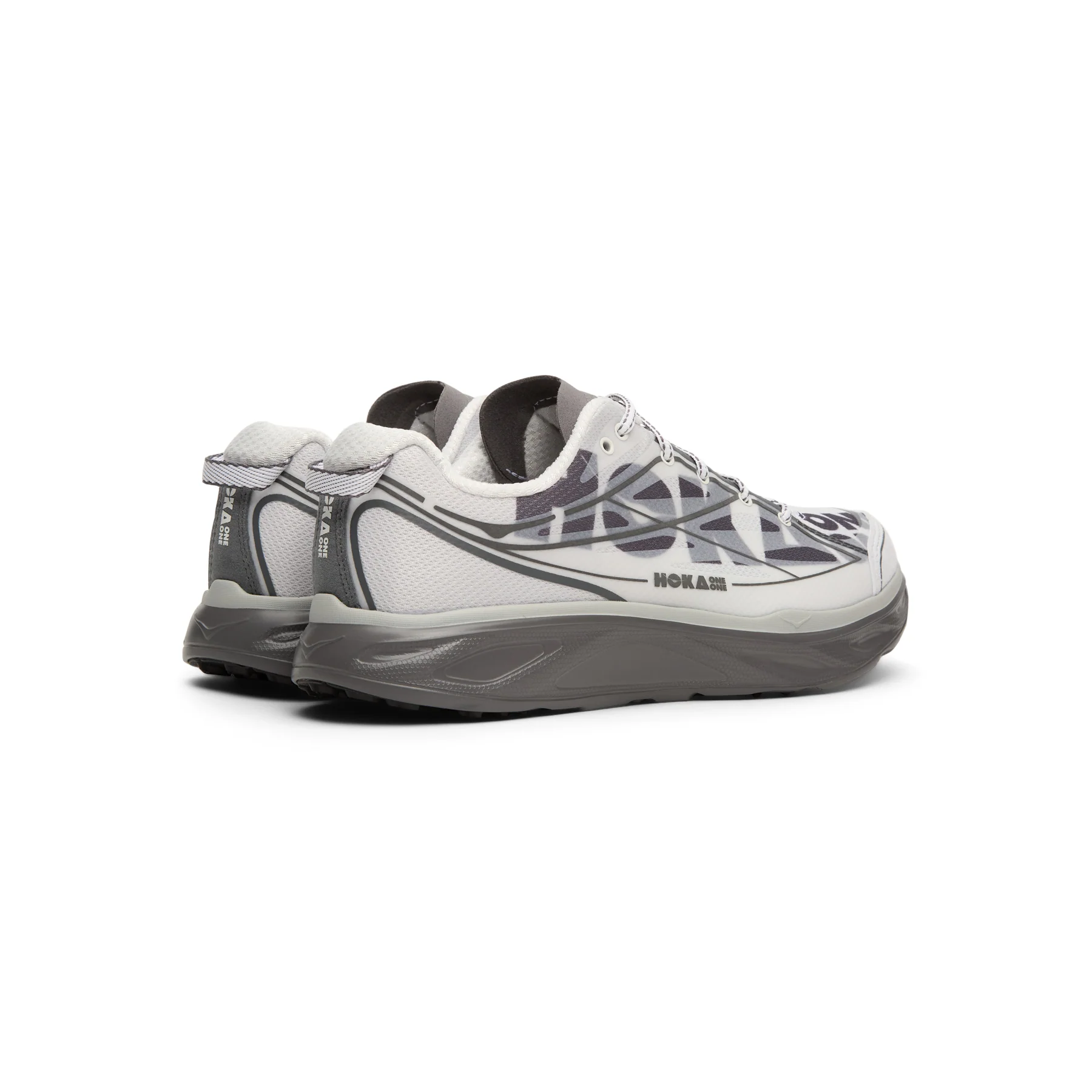 Rear three-quarter view of a pair of HOKA Huaka Pro sneakers in the Cosmic Grey and Satellite Grey colorway, featuring translucent graphic overlays, white mesh uppers, gray heel tabs with HOKA branding, sculpted gray midsoles, and black rubber outsoles on a clean white background.