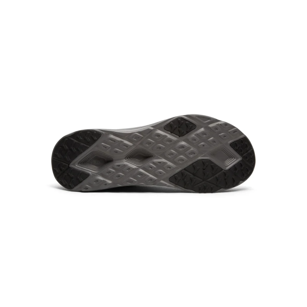 Bottom view of the HOKA outsole displaying a gray molded sole with geometric traction patterns, strategically placed black rubber grip pods at the heel and forefoot, and a central cutout for weight reduction and flexibility