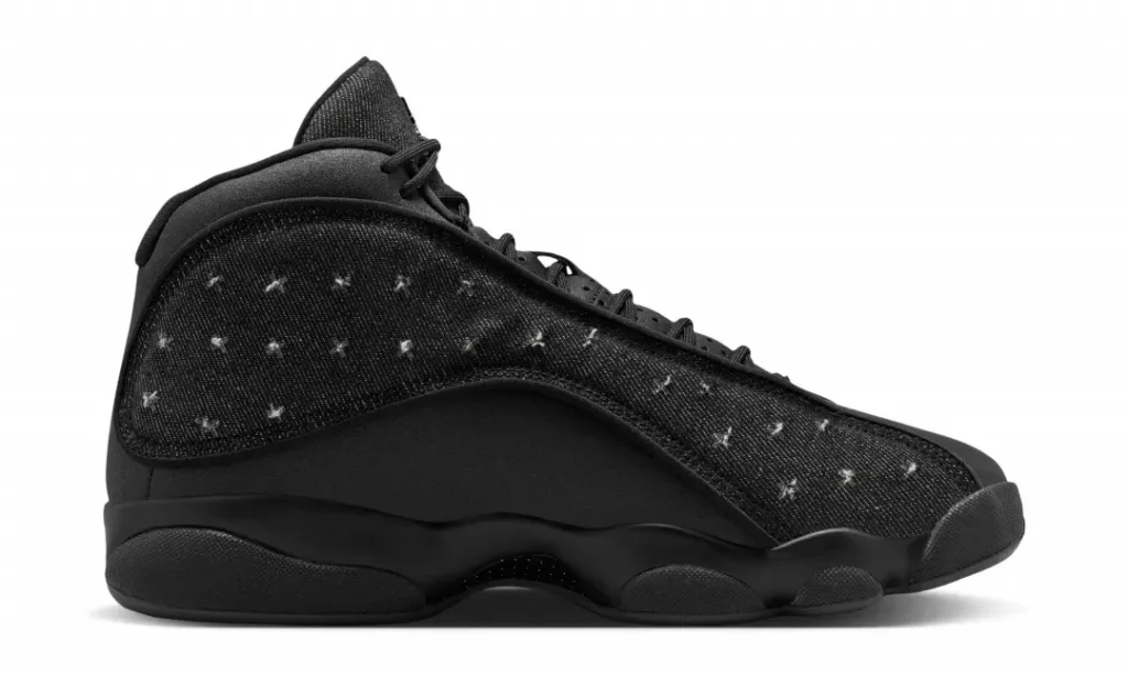 Medial side profile highlights the monochromatic black upper, distressed denim paneling, sculpted midsole, and classic Air Jordan 13 sil