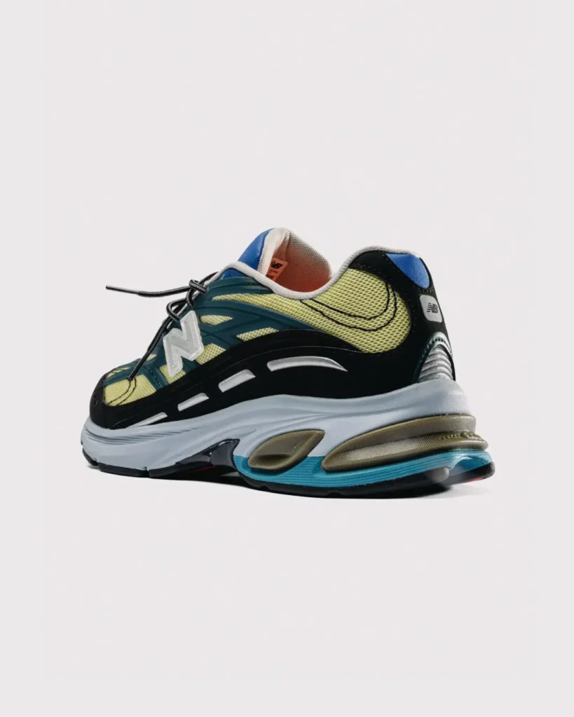 Rear three-quarter view of the New Balance x Baklava 281, showing the oversized heel cushioning, black support frame, blue heel trim, and lime mesh upper