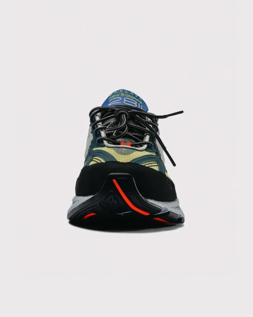 Front-facing view of the New Balance x Baklava 281, focusing on the black suede toe cap, bright orange outsole accents, layered lacing system, and blue branded tongue