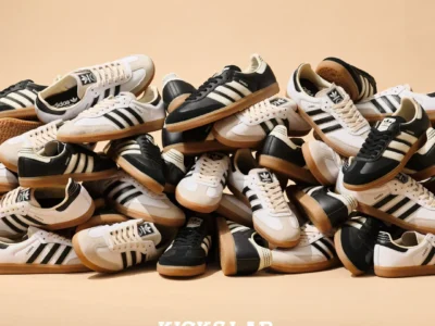 Pile of black and white adidas Samba shoe with gum soles stacked together for a KICKS LAB campaign against a beige studio backdrop