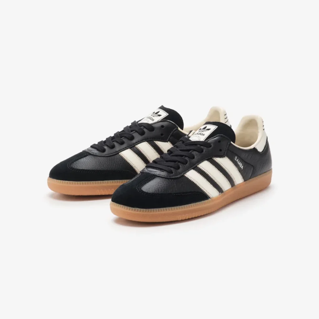 Black adidas Samba sneaker with off-white Three Stripes, suede toe overlay, and gum rubber sole shown in a three-quarter view