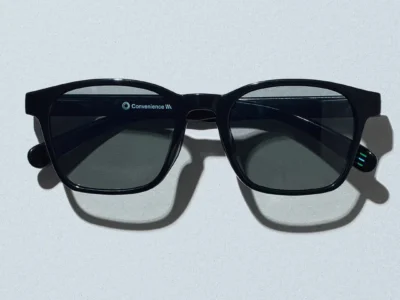 Black square frame Convenience Wear sunglasses photographed from the front against a light gray background, featuring dark polarized lenses, subtle Convenience Wear branding on the inner temple, and the signature FamilyMart blue and green stripes at the temple tip