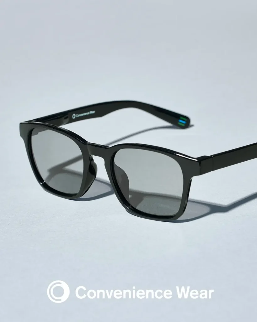 Three quarter angled product shot highlighting the glossy black square frame, dark lenses, slim profile, and minimalist design. The Convenience Wear logo is visible on the inside temple, with the blue and green striped temple tip adding a subtle brand accent