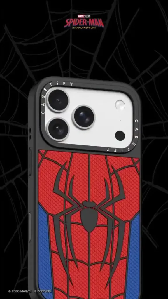 Angled close-up of the Spider-Man themed CASETiFY phone case highlighting its textured red web pattern, matte black spider emblem, blue lower side accents, black protective frame, and precision camera cutout with branded camera ring