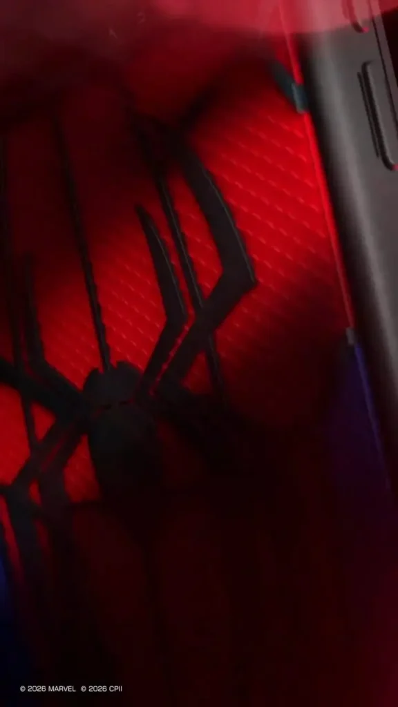Extreme close-up of the case's embossed red web texture and raised black spider logo, revealing the tactile finish, sculpted detailing, and black protective frame illuminated by cinematic red light
