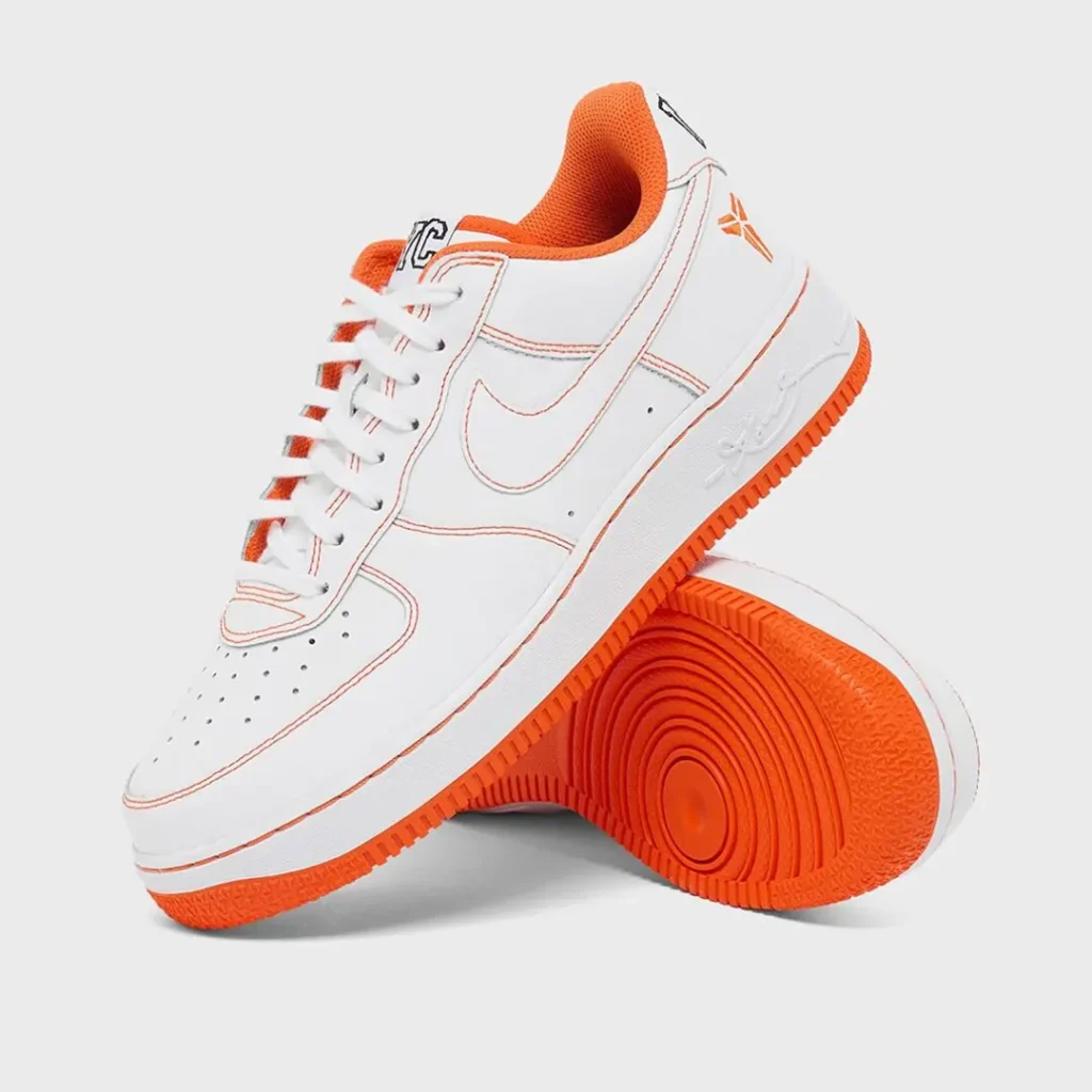 White and orange Nike Air Force 1 Low featuring Kobe Bryant-inspired detailing, orange contrast stitching, white leather upper, bright orange outsole, and stacked studio presentation against a light gray background