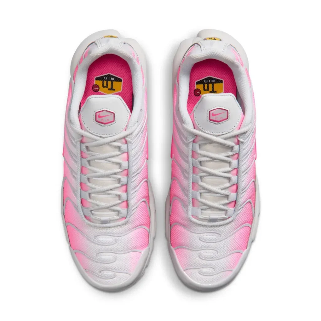 Overhead view of the Air Max Plus pair featuring gradient pink mesh, gray laces, padded collars, and Tuned Air-branded insole